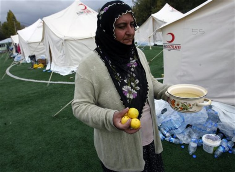 An unidentified earthquake survivor carries free soup and lemons distributed by Turkish Red Crescent in a tent city set up in a soccer field in Ercis, Van, Turkey, Thursday, Oct. 27, 2011. The death toll after the powerful Sunday quake hit eastern Turkey has now reached over 500. (AP Photo/Burhan Ozbilici)